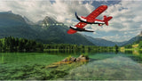 Red RC airplane model flying low over a lake, black wing stripes visible