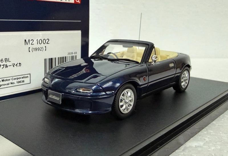 1:43 scale convertible model car, dark blue with tan interior, front three-quarter view.