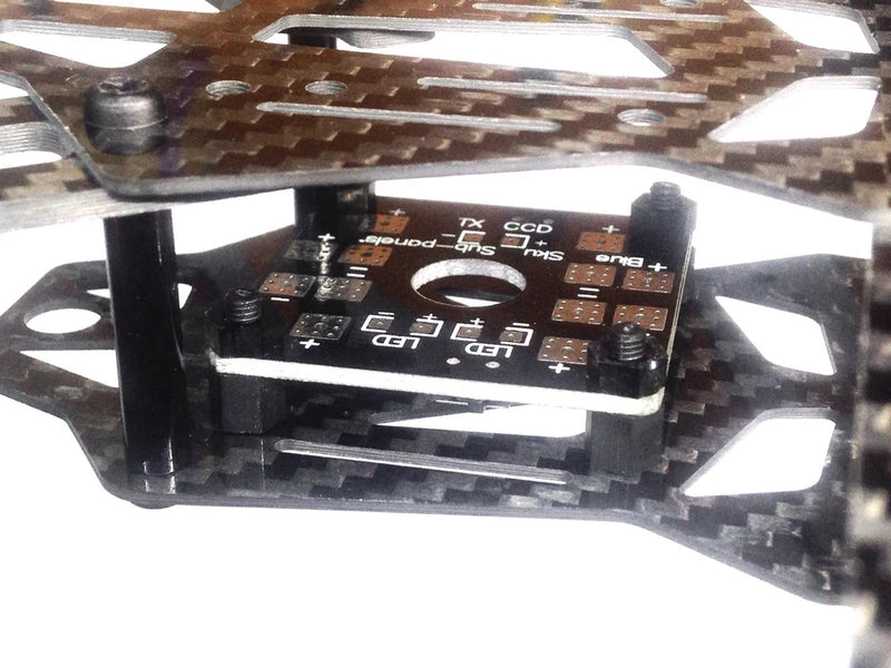 Quadcopter power distribution PCB with labeled connectors on carbon fiber frame
