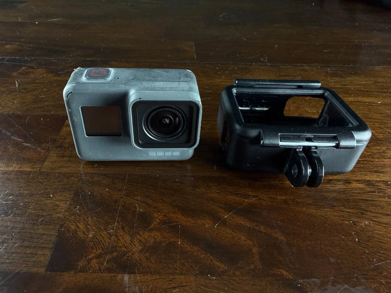 GoPro action camera with front lens and small screen, plus black wrap-around mount