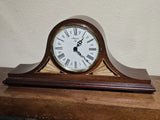 Traditional mantel clock with brown wood case, brass accents, and Roman numeral dial