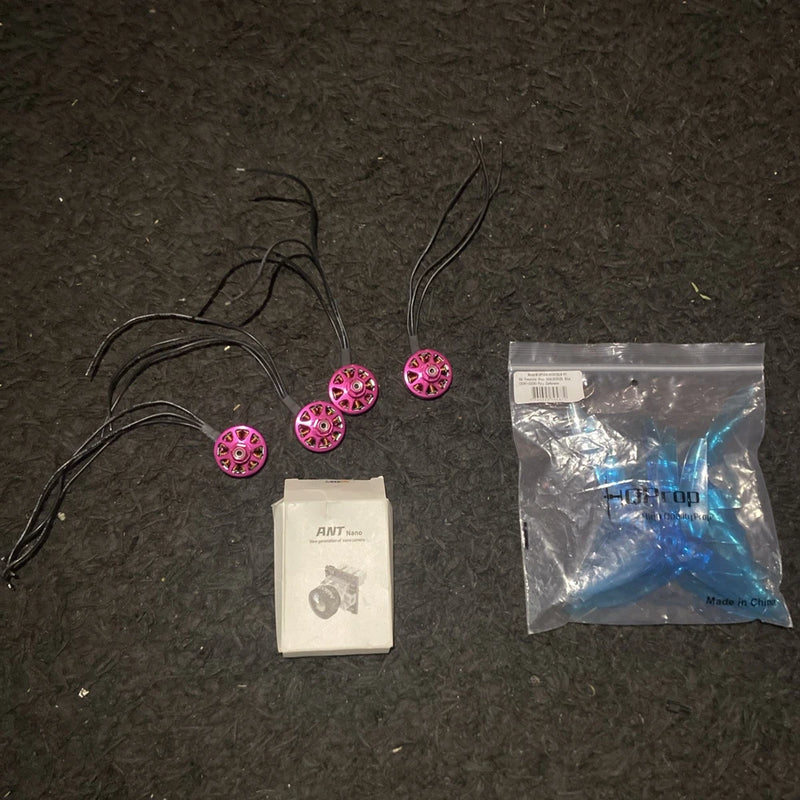 FPV drone part set with pink circular components, wires, and spare bag