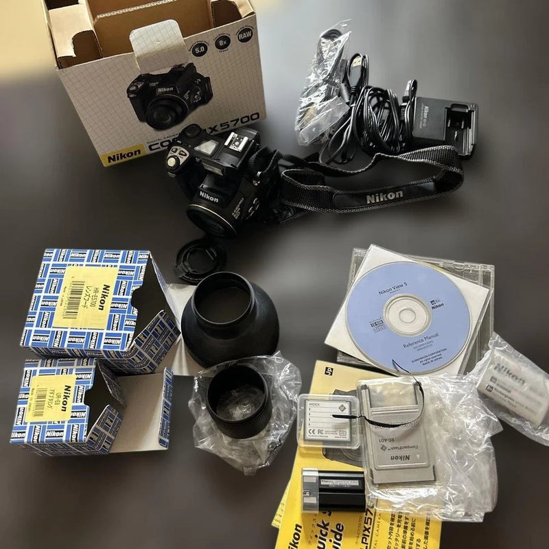 Nikon COOLPIX digital camera with lens, strap, cables, and accessory discs