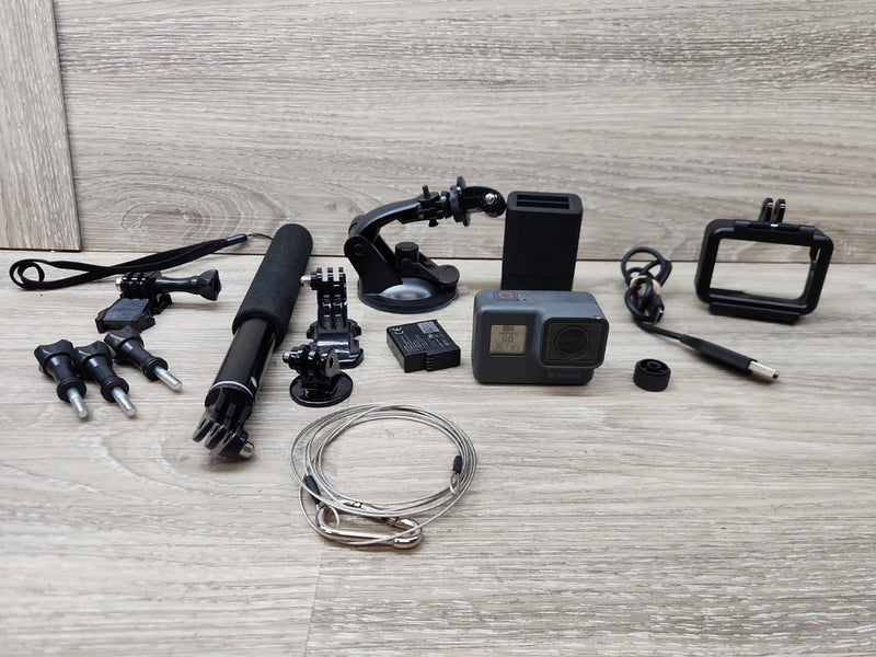 Gray action camera with mounts, battery, cables, and waterproof housing on a table