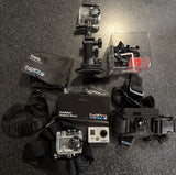 Silver GoPro HERO2 action camera with chest mount and accessory bundle