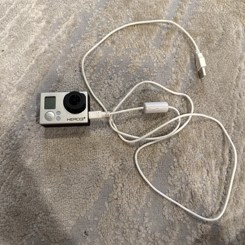GoPro HERO3+ Plus action camcorder with front lens, screen, and white cable