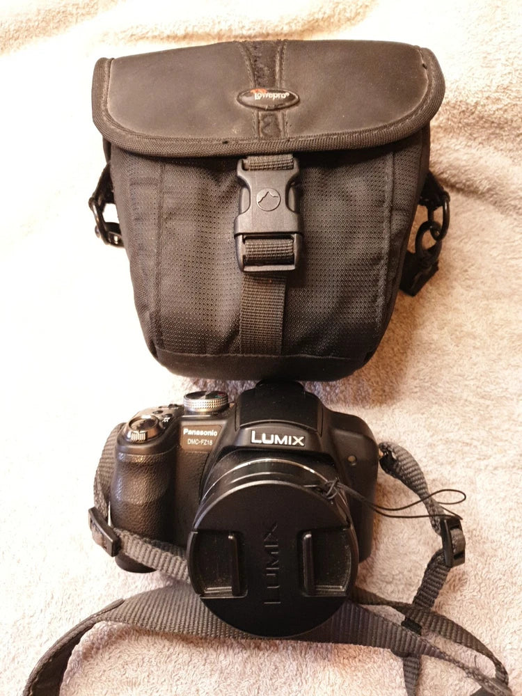 Black digital bridge camera with gray carry case and attached strap, front view.