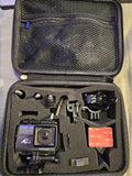 Action camera kit in open zip case with camera, mounts, cables, and memory card