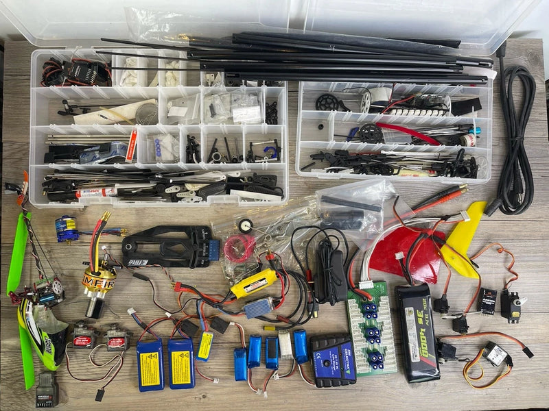 RC hobby parts bin with brushless motors, servos, receiver, wiring, LiPo batteries