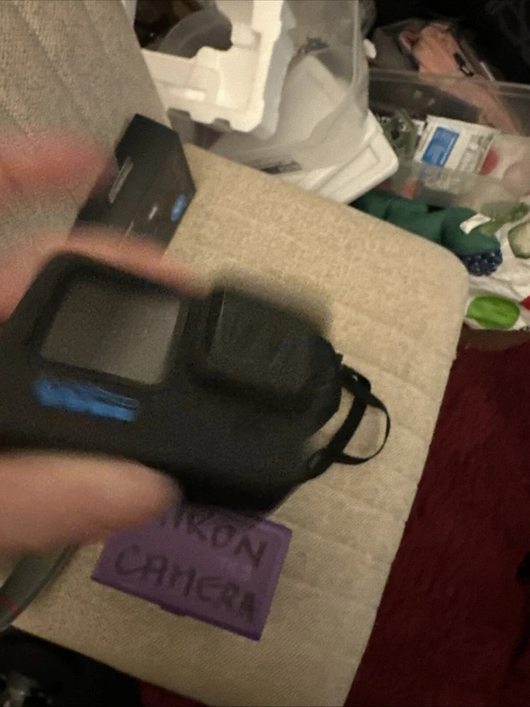 Black action camera with front display and wrist strap, close-up
