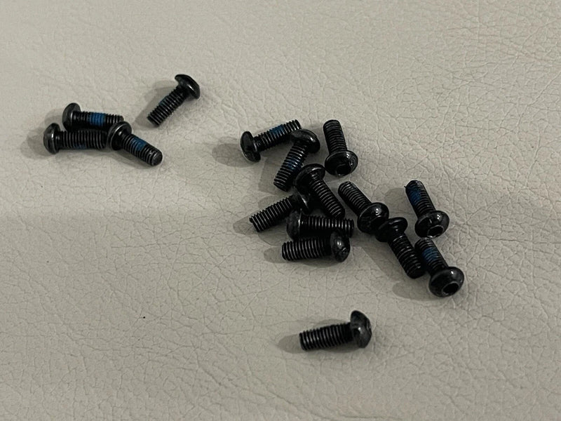 16-piece black metal RC drone screws, mixed sizes, loose hardware on surface