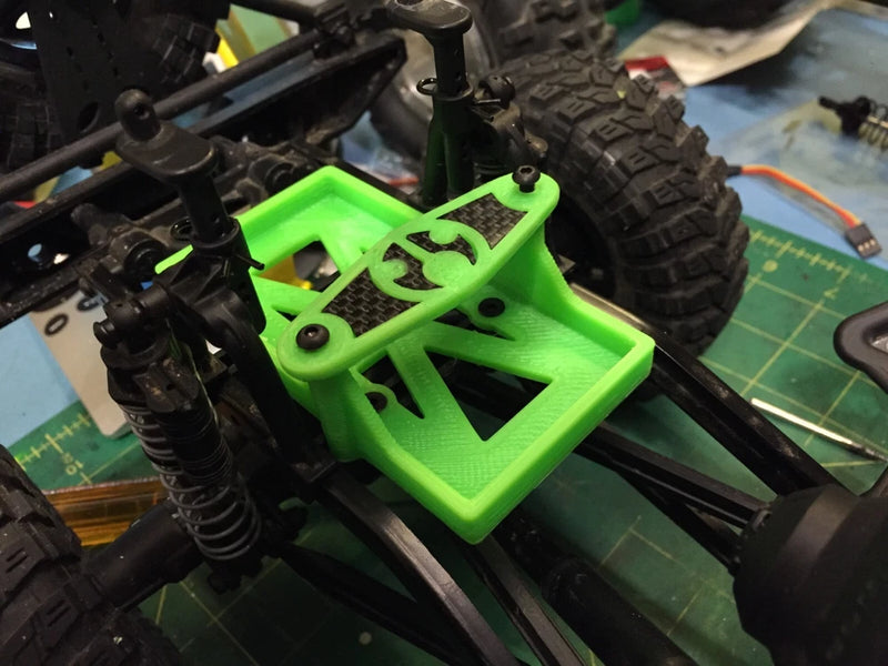 Bright green RC battery tray with mounting holes and straps, installed on chassis frame
