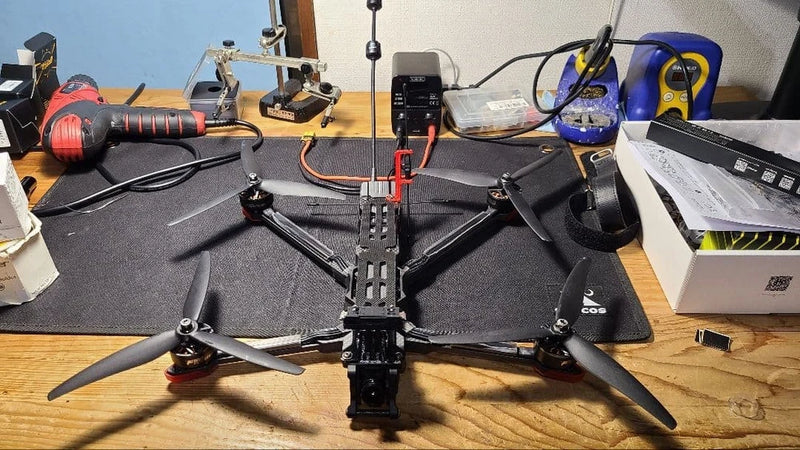 FPV quadcopter drone kit with four black propellers and camera module on mount