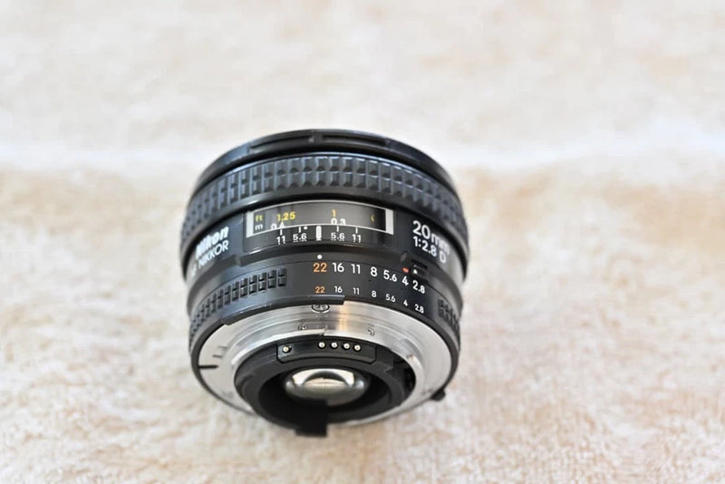 Black wide-angle camera lens with front glass and engraved focus distance markings
