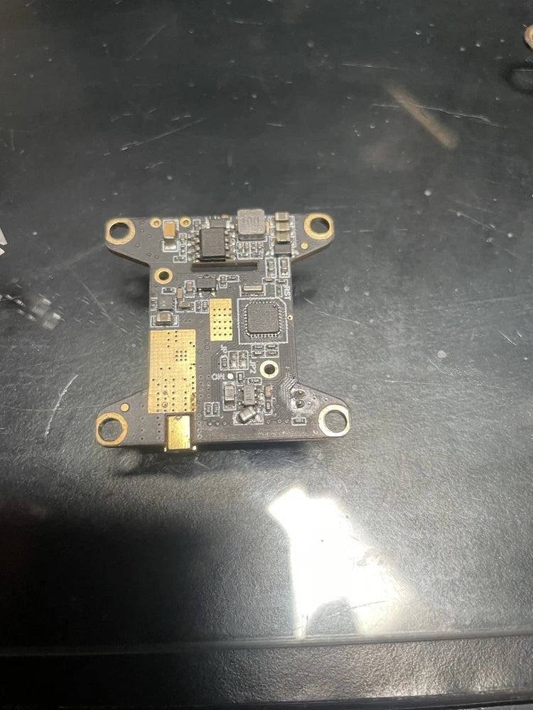 Drone flight controller PCB with microchips and four mounting holes, gold pads visible
