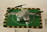 Foldable gray quadcopter drone with 4 rotors, camera body, arms folded.