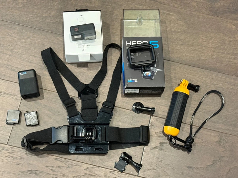 Action camera bundle with black action camera, head strap, mounts, and selfie stick.