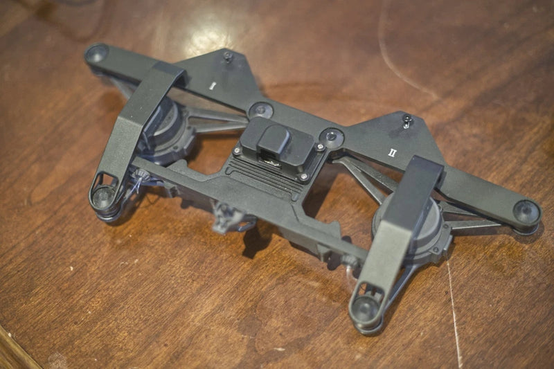 Dark gray drone chassis with dual downward gimbal arms and mounting plate