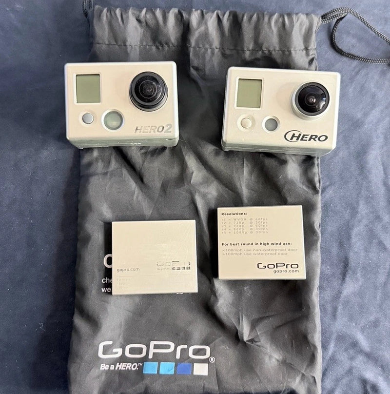 GoPro action cameras, two white front panels with LCD and circular lens, HERO2/HERO