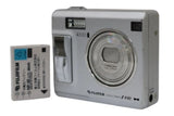 Silver compact digital camera with zoom lens and flash; includes battery pack