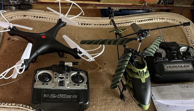 Drone and helicopter lot with two black quadcopters and a handheld controller