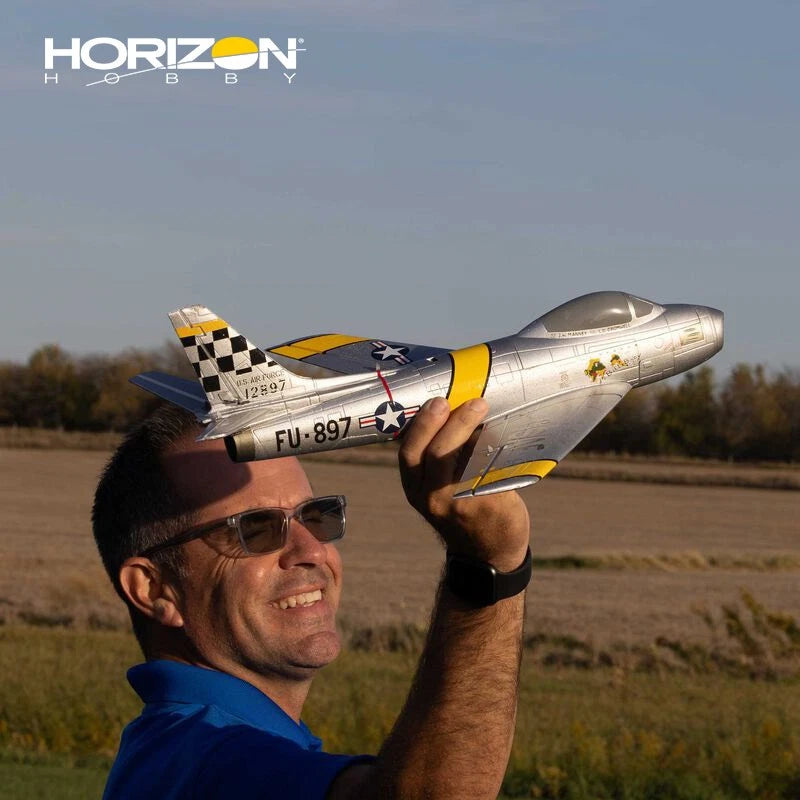 RC jet model aircraft with silver fuselage, checkered nose, and yellow accents, handheld