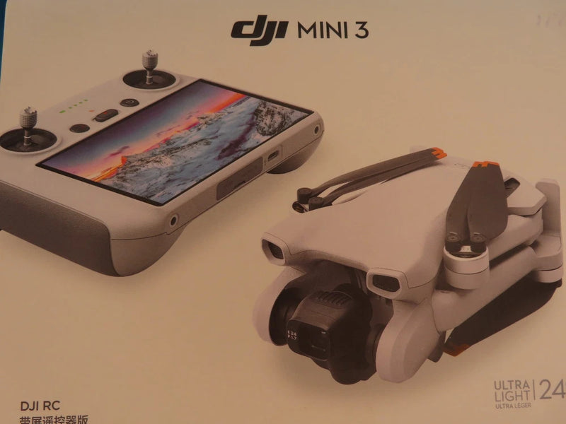 DJI Mini 3 drone with white controller and handheld remote, screen showing map