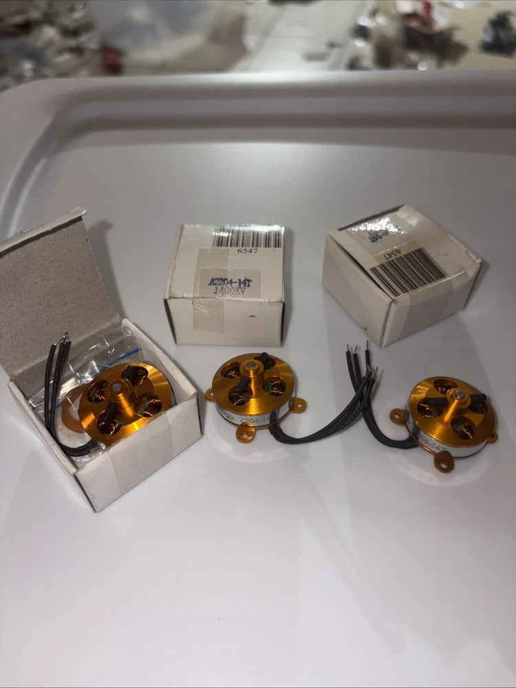 Set of gold outrunner electric motors with black wires in retail boxes