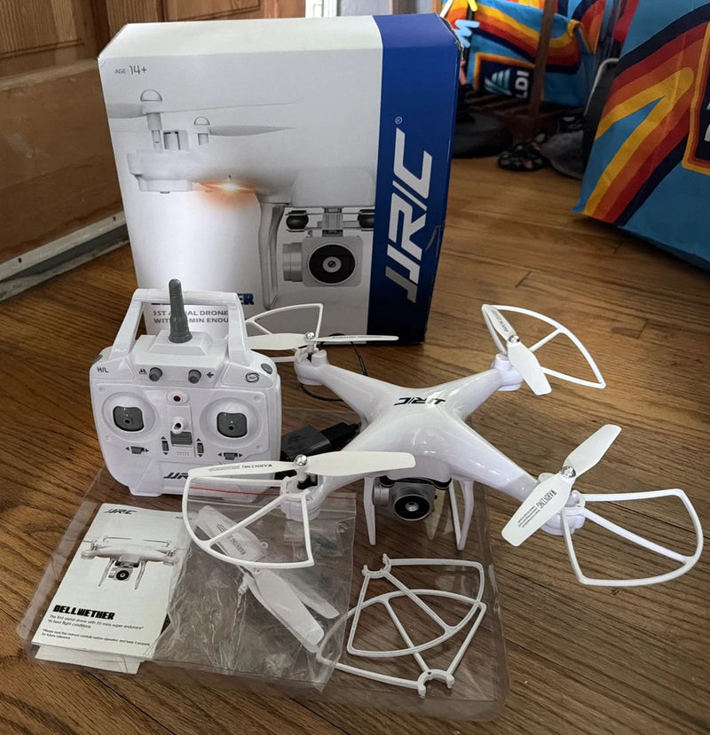 White JJRC aerial drone with four propellers, remote controller, and box