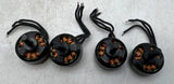 Set of four black brushless RC motors with copper windings and attached wiring