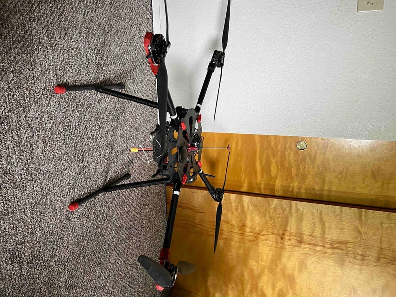 Black quadcopter drone with four propellers and central camera mount
