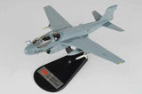 Light blue military jet model aircraft on black display stand, angled side view