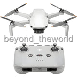 White quadcopter drone with 4 propellers and gray remote controller, front view