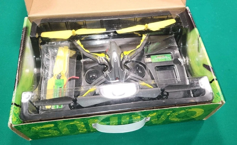 Yellow and black quadcopter drone with propellers, shown in open retail box