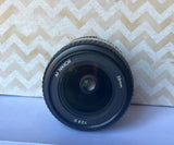 Black AF NIKKOR 28mm f/2.8 D camera lens with front glass and metal ring