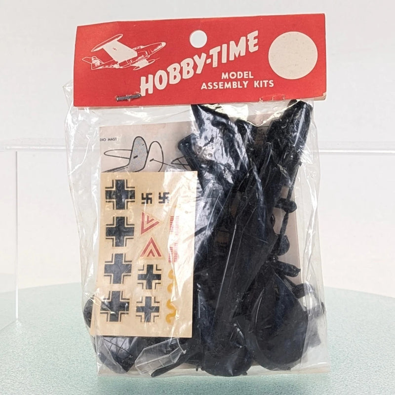 Sealed model plane kit bag with black plastic parts and decal sheet with cross markings