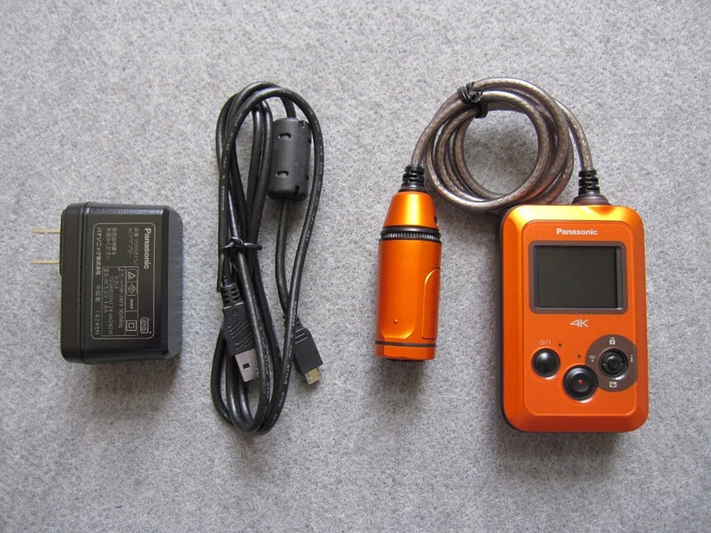 Panasonic wearable camera, orange, with LCD screen and 4K label, plus charging cable