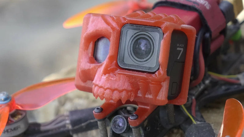 GoPro action camera in orange skull-shaped mount with side buttons visible