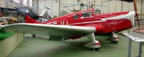 Wood airplane model replica with red fuselage and green wings on display stand