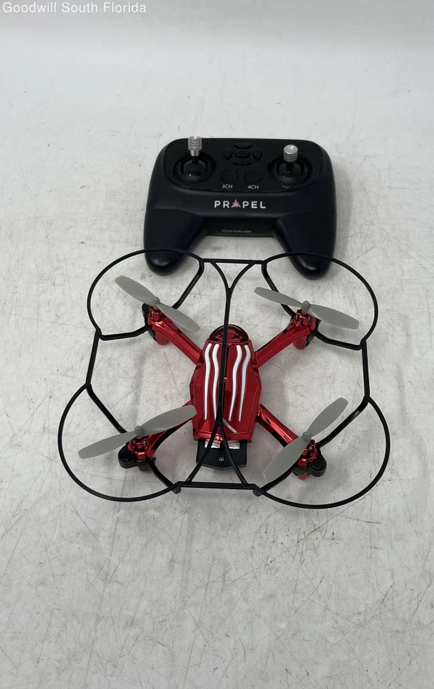 Palm-sized RC drone in black and red with visible propellers, top view