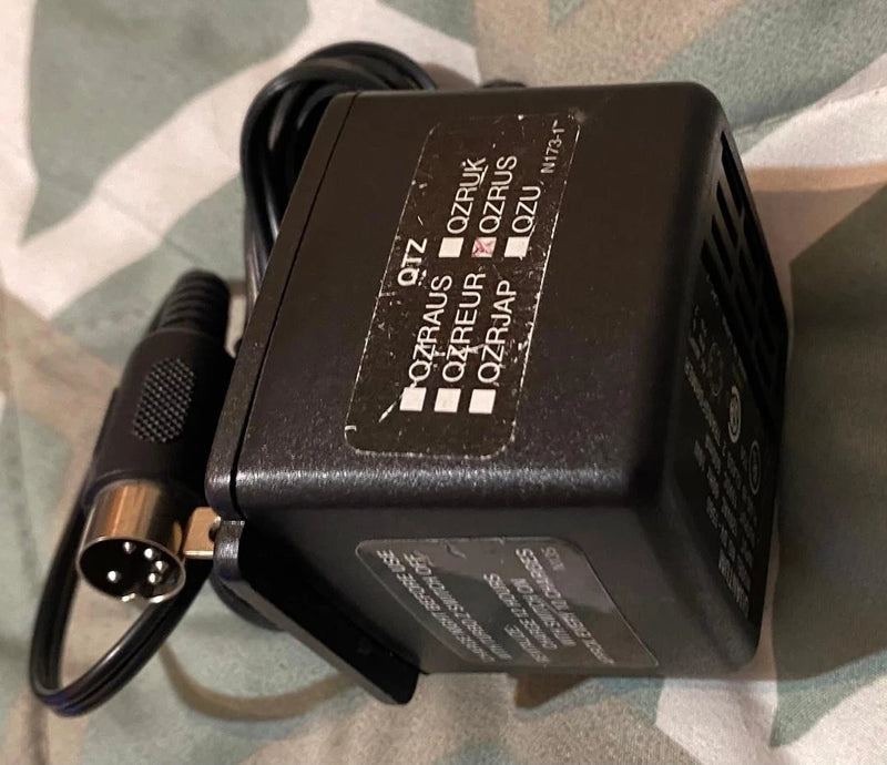 Black battery charger with side plug and printed label, attached power cord
