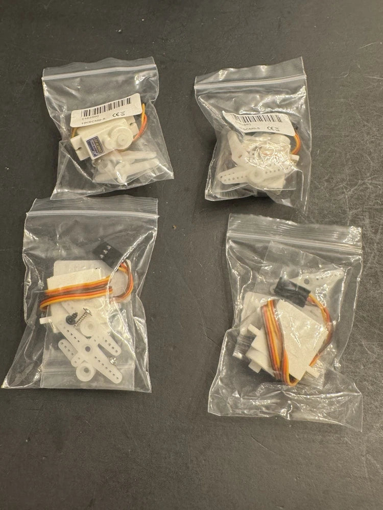 Four micro RC servos in clear plastic bags with mounting hardware