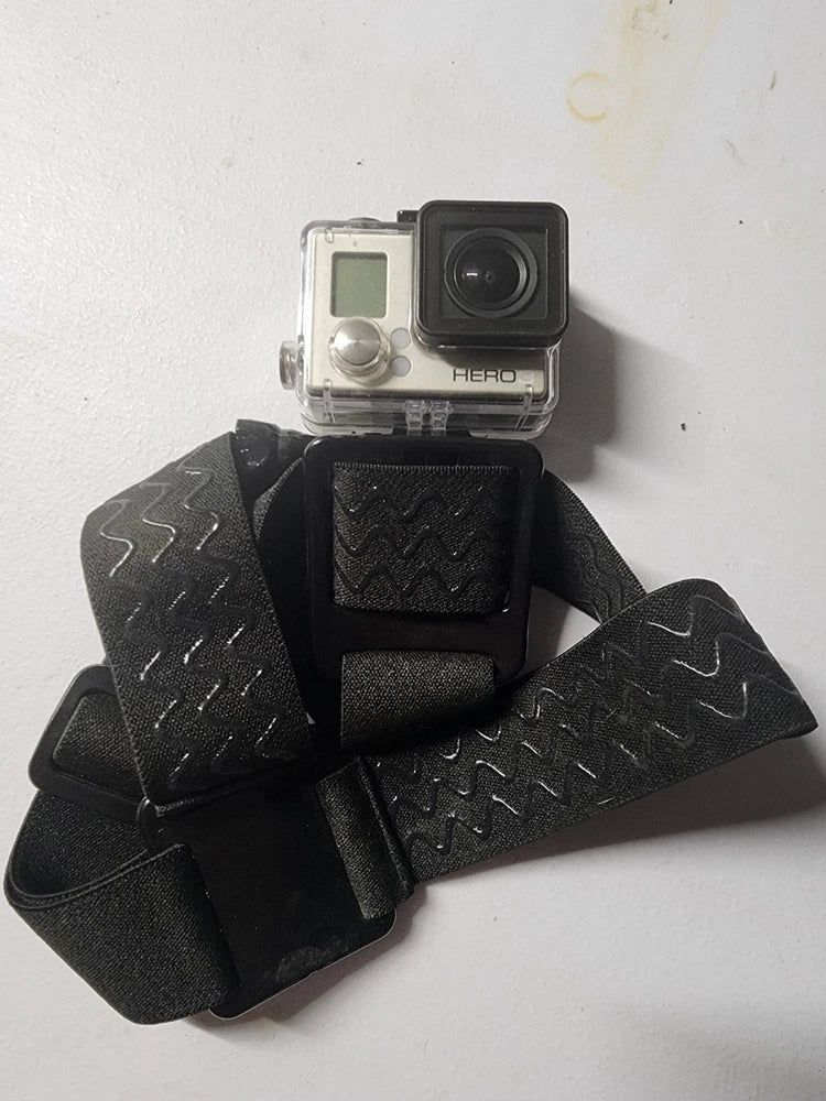 Silver action camera in black waterproof case with padded head strap, close-up