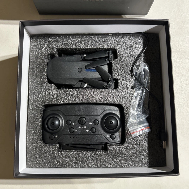 Foldable quadcopter drone and remote controller in open box, black