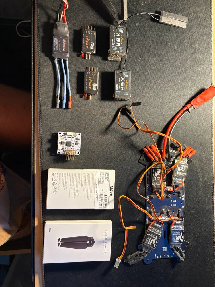 FPV drone parts lot with circuit boards, ESC modules, and flight controller