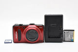 Red compact digital camera with lens, Fujifilm logo; open battery cover and battery included.