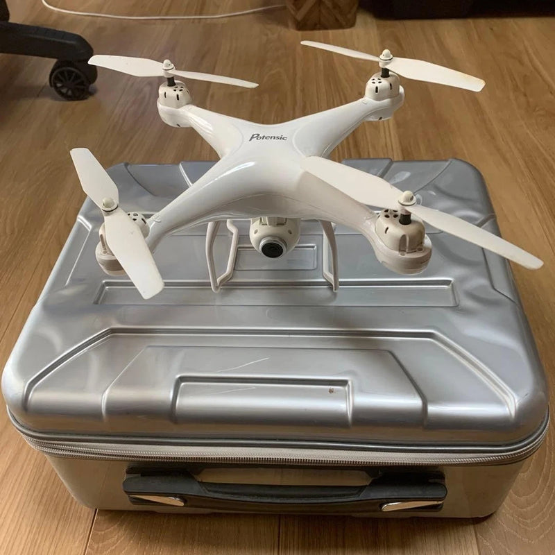 White quadcopter drone with camera and four propellers, shown on a carrying case base