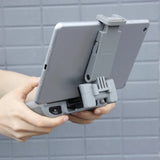 Foldable tablet expansion bracket with adjustable clamp, holding a tablet in place