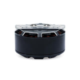 Drone motor with black cylindrical housing and silver top plate, visible copper windings