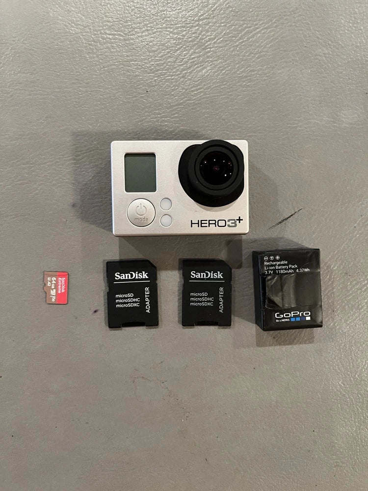 Silver action camera with black lens, plus two SanDisk microSD cards and GoPro mount card